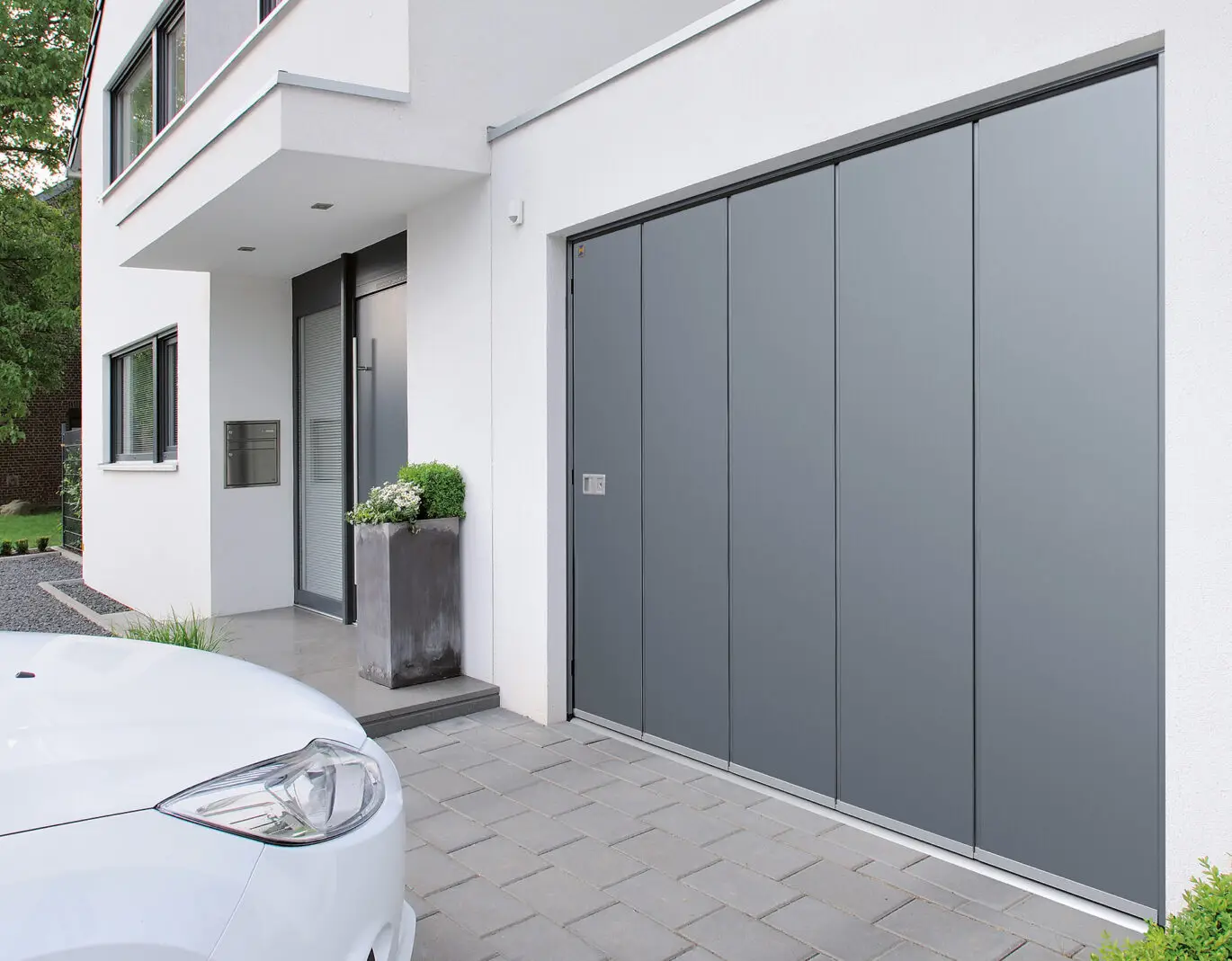 Zijwaartse sectionaalpoort in een lichtgrijze gevel – garagepoorten Ieper