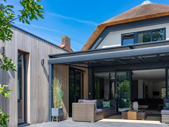 Modern huis in Tielt met veranda zonwering - Windvaste screens op terrasoverkapping met houten gevelbekleding