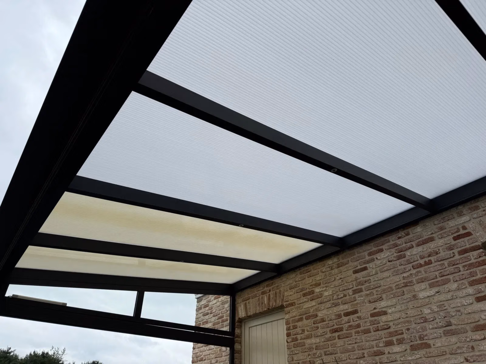 Polycarbonaat platen vervangen op een terrasoverkapping: nieuwe meerwandige platen in aluminium profielen