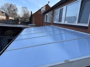 Hellende terrasoverkapping met polycarbonaat dakplaten tegen bakstenen gevel in Menen